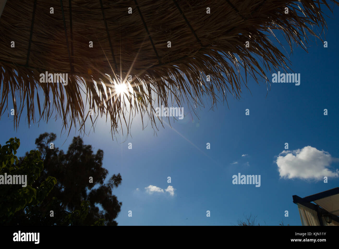 Stroh, Sonnenschirm und Blick in den Himmel mit der Sonne Stockfoto