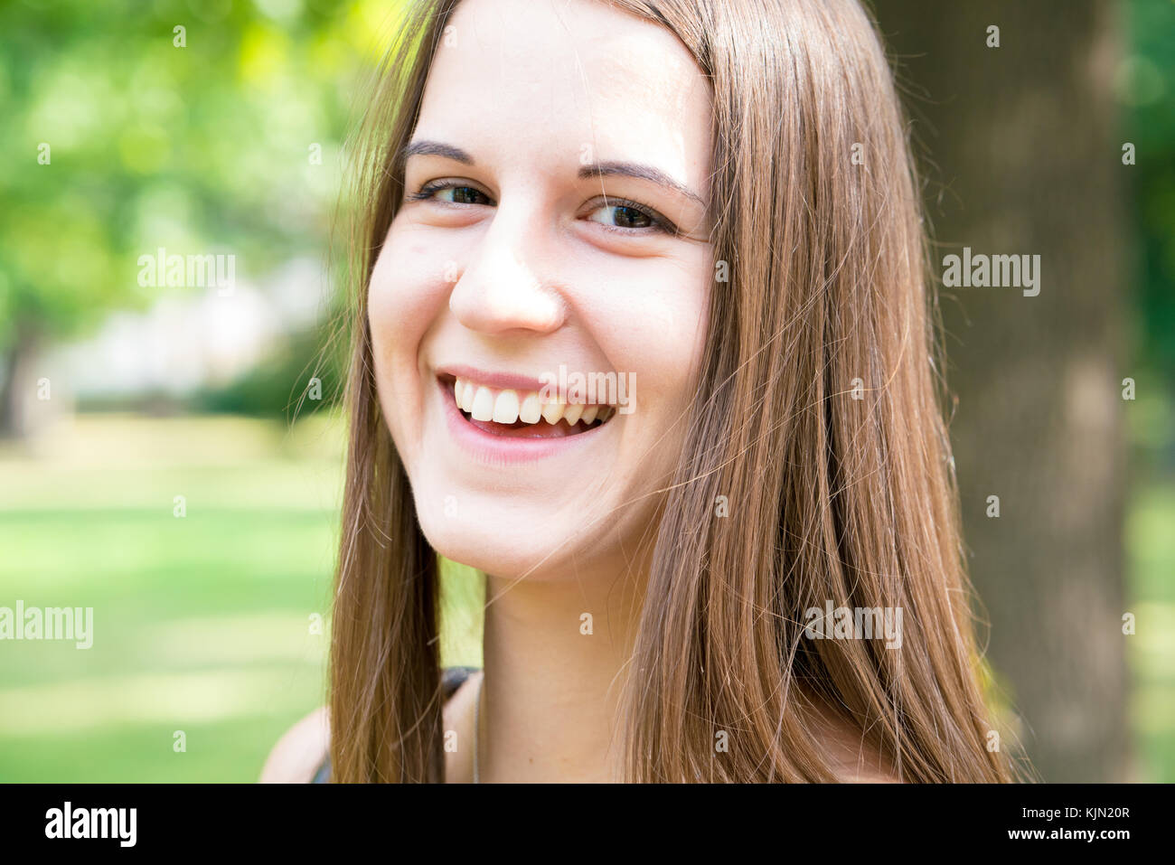 Portrait junge lächelnde Frau mit langem Haar im Sommer Park Stockfoto