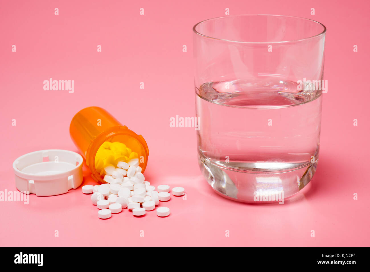 Pillen und Medikamente und ein Glas Wasser auf einem roten Hintergrund Stockfoto