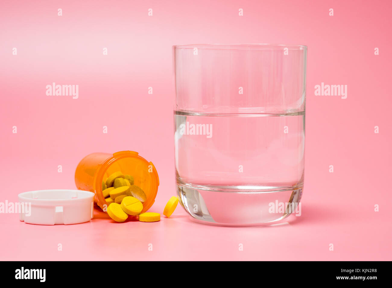 Pillen und Medikamente und ein Glas Wasser auf einem roten Hintergrund Stockfoto