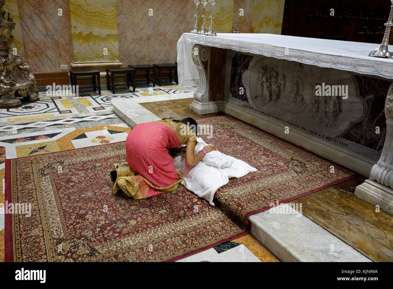 Eine katholische Frau aus Indien kniet sich im Gebet über ihr neugeborenes Baby nach der Taufe Taufe im franziskanischen Heiligen Retter oder Kirche San Salvador in Saint Francis Straße im christlichen Viertel in der Altstadt Ost Jerusalem Israel Stockfoto