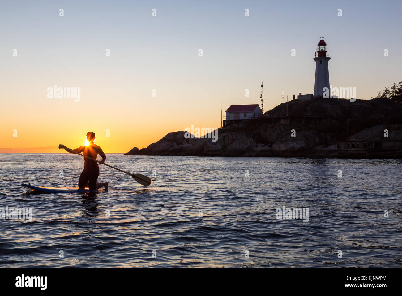 Frau Paddle Boarding durch die lighthouse Park während einer lebhaften sonnigen Sonnenuntergang. in West Vancouver, British Columbia, Kanada. Stockfoto