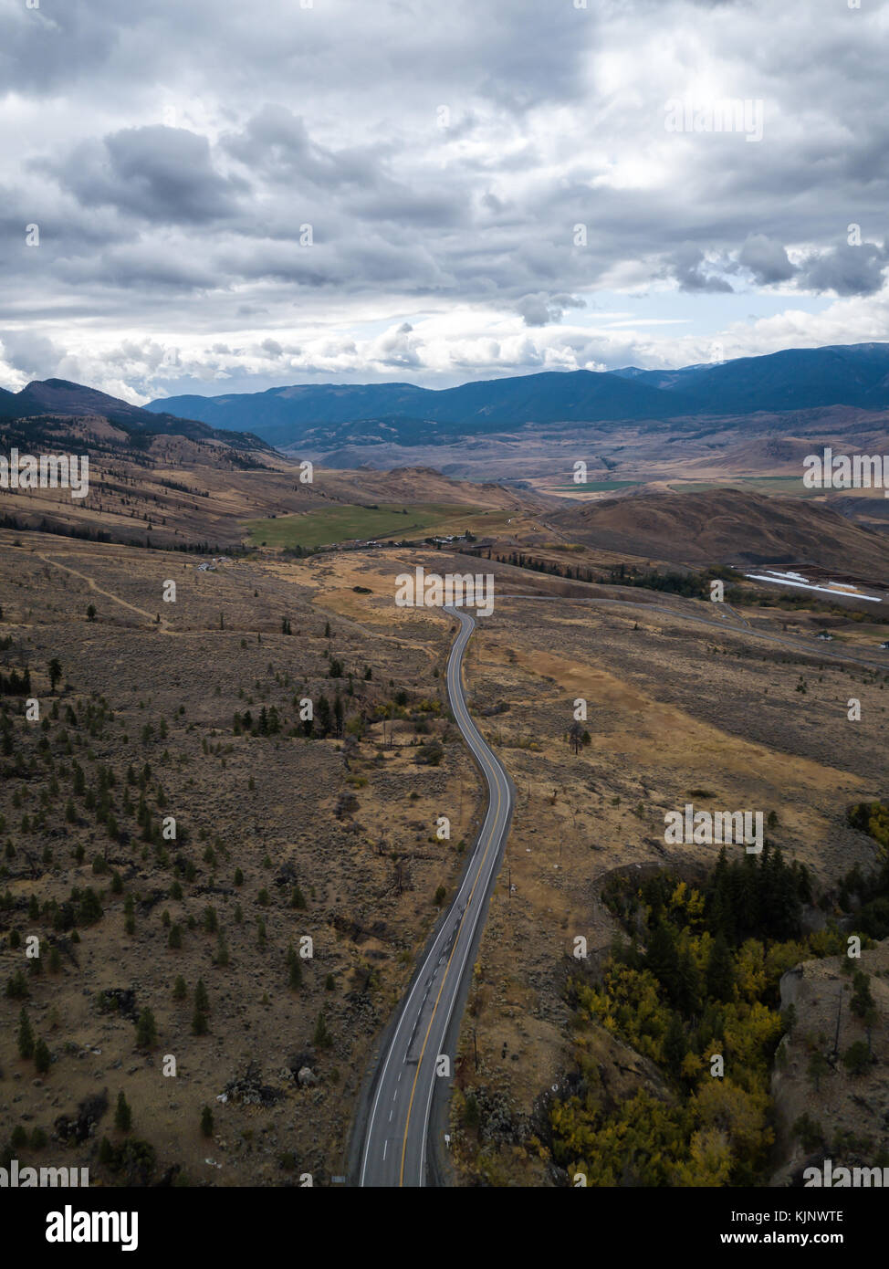 Antenne drone Landschaft Blick auf eine Straße, die durch das kontinentale Klima Felder bei einem bewölkten Herbst Tag. Im Inneren von Britisch-Kolumbien, Stockfoto
