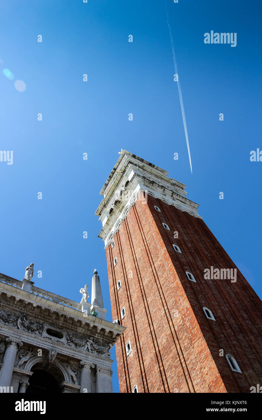 Venedig, Italien, 9. Mai 2015, schräger Blick auf die Camanile auf der Piazza San Marco mit klarem, blauem Himmel und Flugzeug Kondensstreifen Stockfoto