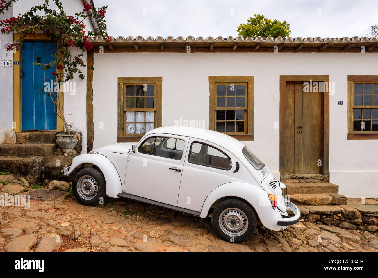 Weiße Kolonialhausfenster, weißer Volkswagen Käfer, Kopfsteinpflasterstraße, Tiradentes, Minas Gerais, Brasilien. Stockfoto