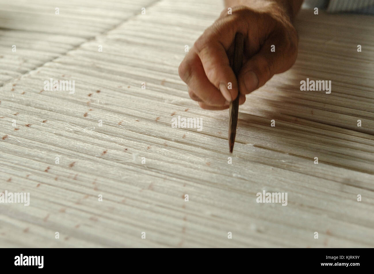 Hand mit einem Bleistift macht Flecken auf dem Teppich. Weberei und der Herstellung von handgefertigten Teppichen closeup Stockfoto