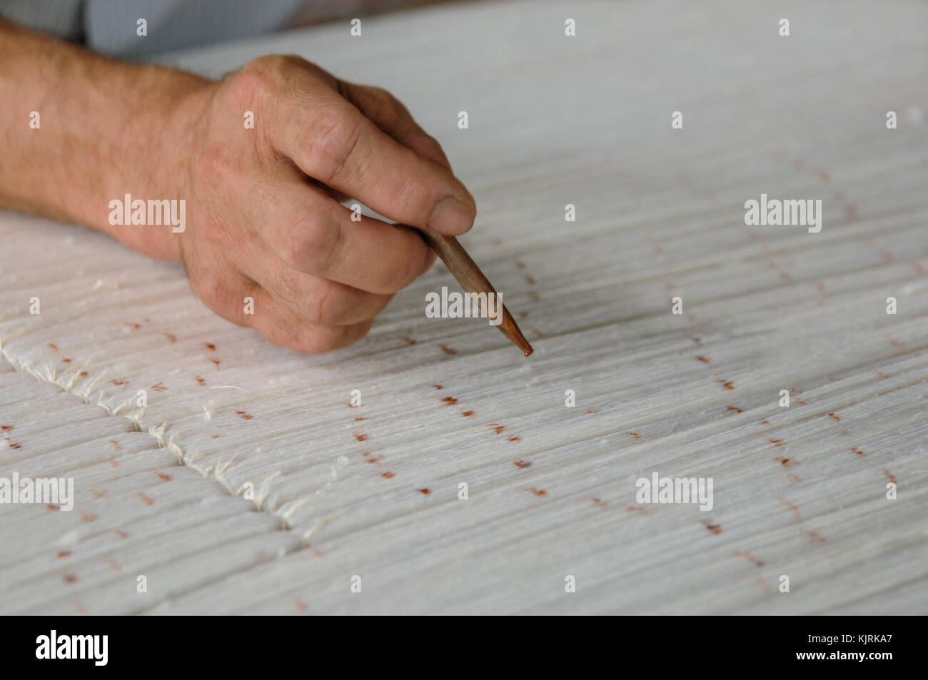 Hand mit einem Bleistift macht Flecken auf dem Teppich. Weberei und der Herstellung von handgefertigten Teppichen closeup Stockfoto