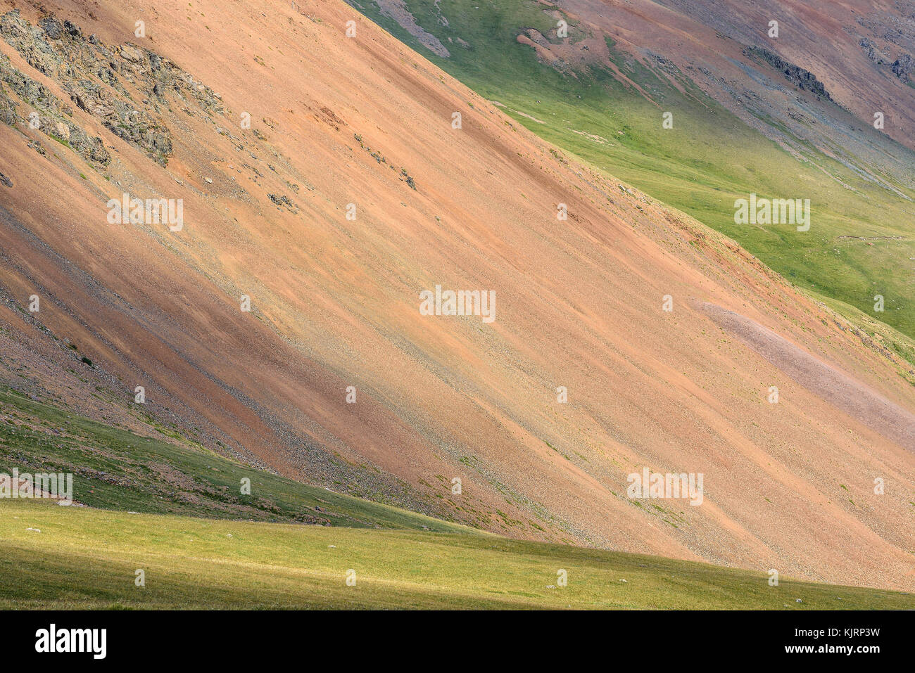 Farbenfrohe abstrakte natürlichen Hintergrund mit Hänge der Berge mit Rosa und braun Geröllhalden, grünes Gras, grauen Steinen und Kies Stockfoto