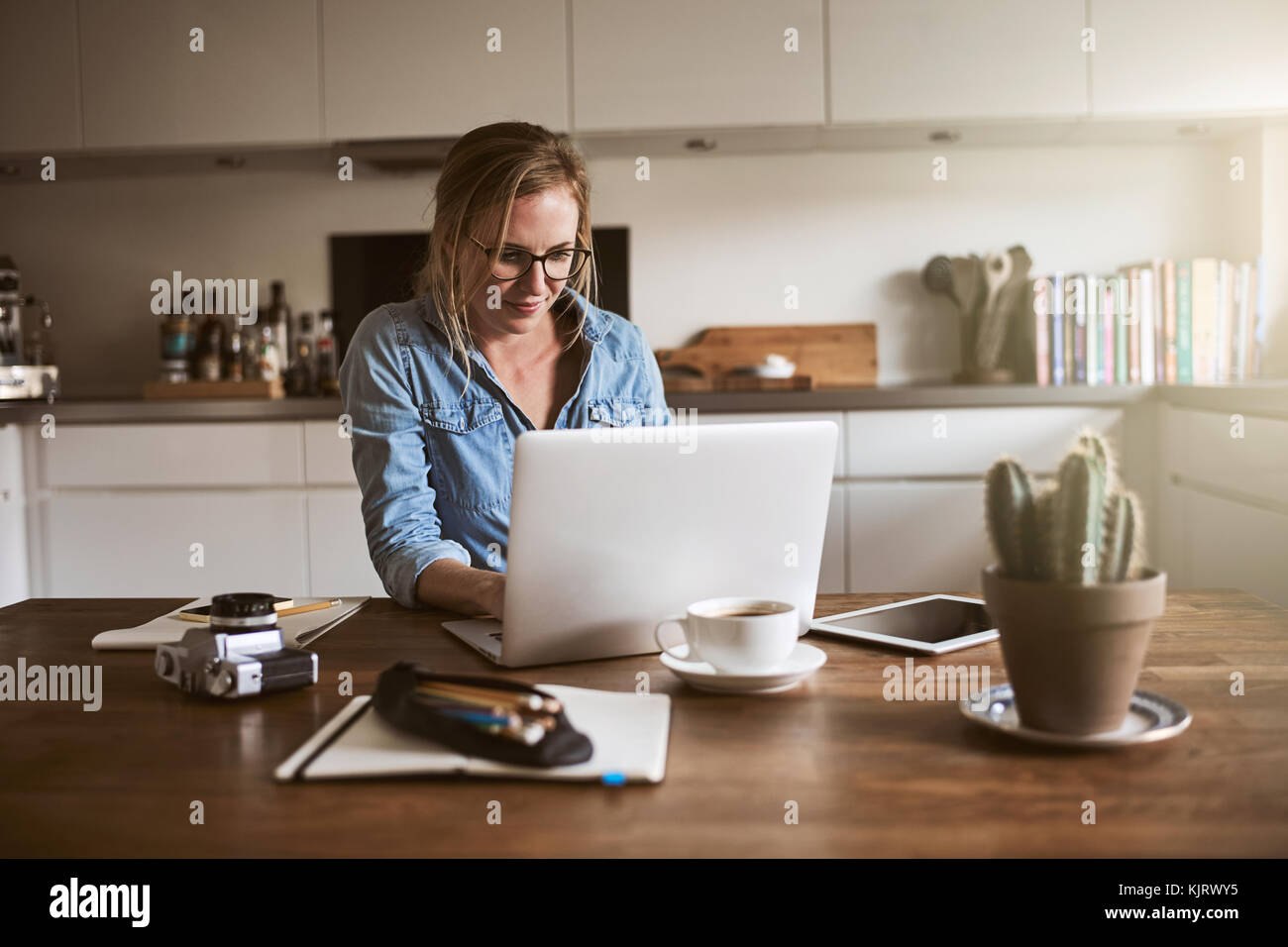 Junge weibliche Unternehmer an ihrem Küchentisch sitzen zu Hause, in Ihrem kleinen Unternehmen mit einem Laptop gerichtet Stockfoto