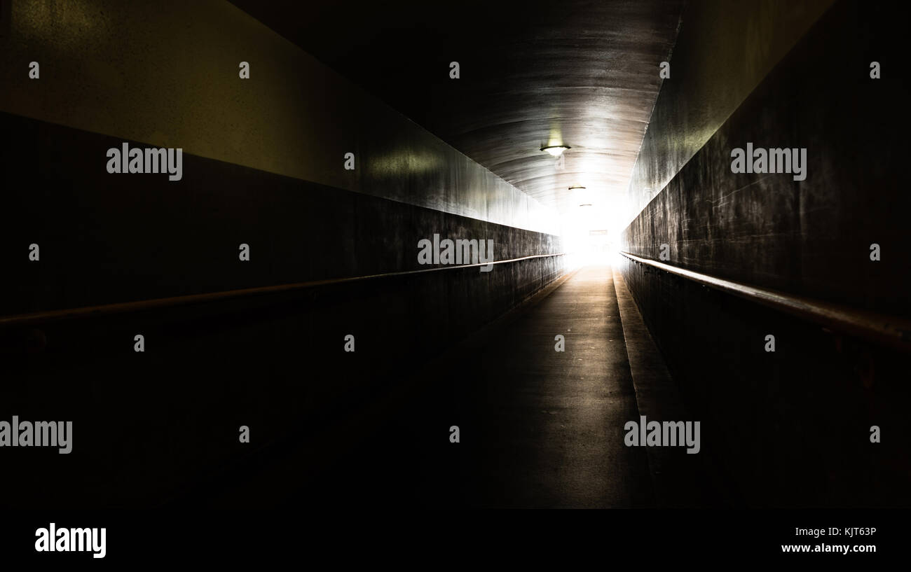 Eine lange Rampe Gehweg u mit Tageslicht am Ende des Tunnels Stockfoto