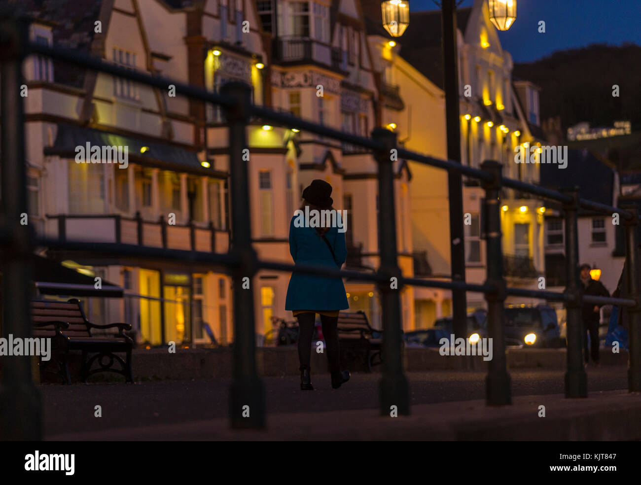 Allein eine Frau spaziert an der Esplanade bei Sidmouth entlang, während der Abend fällt. Stockfoto