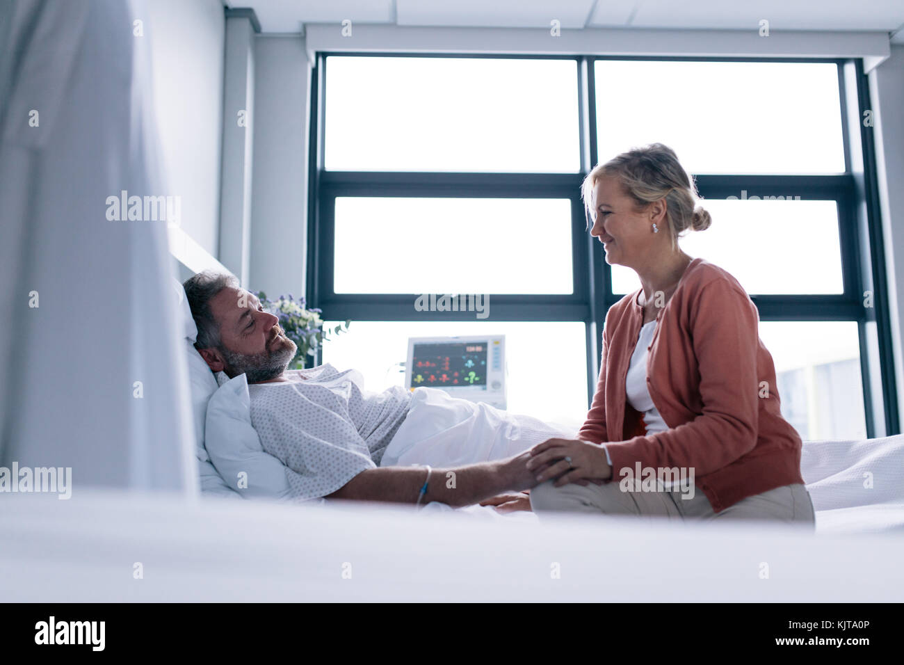 Frau, Mann im Krankenhaus. Weibliche Gespräch mit männlichen Patienten im Krankenhaus Bett lag. Stockfoto
