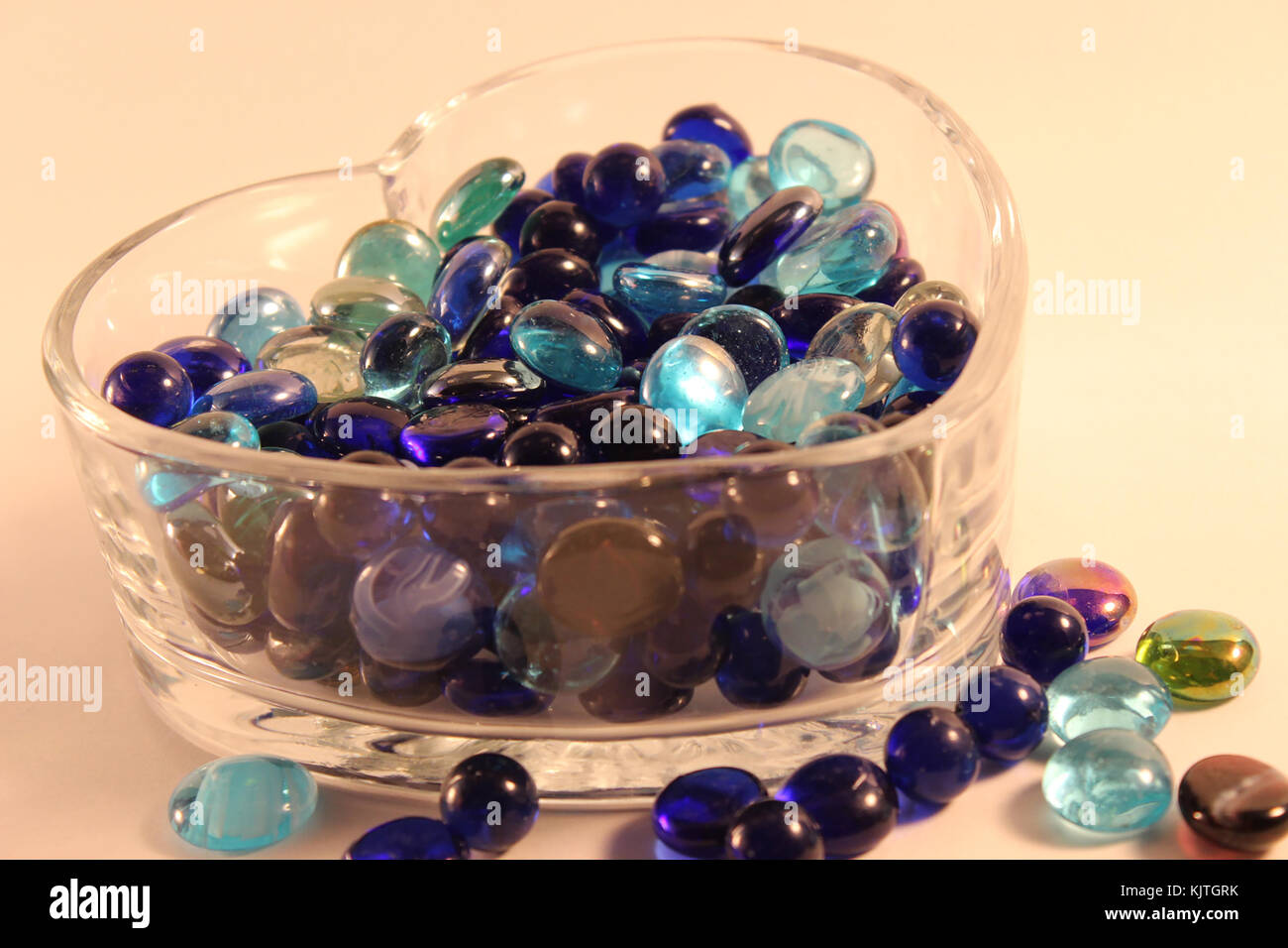 Verschiedene Schattierungen von blauen Glasperlen in Herzform Glas Container auf dem Boden Stockfoto