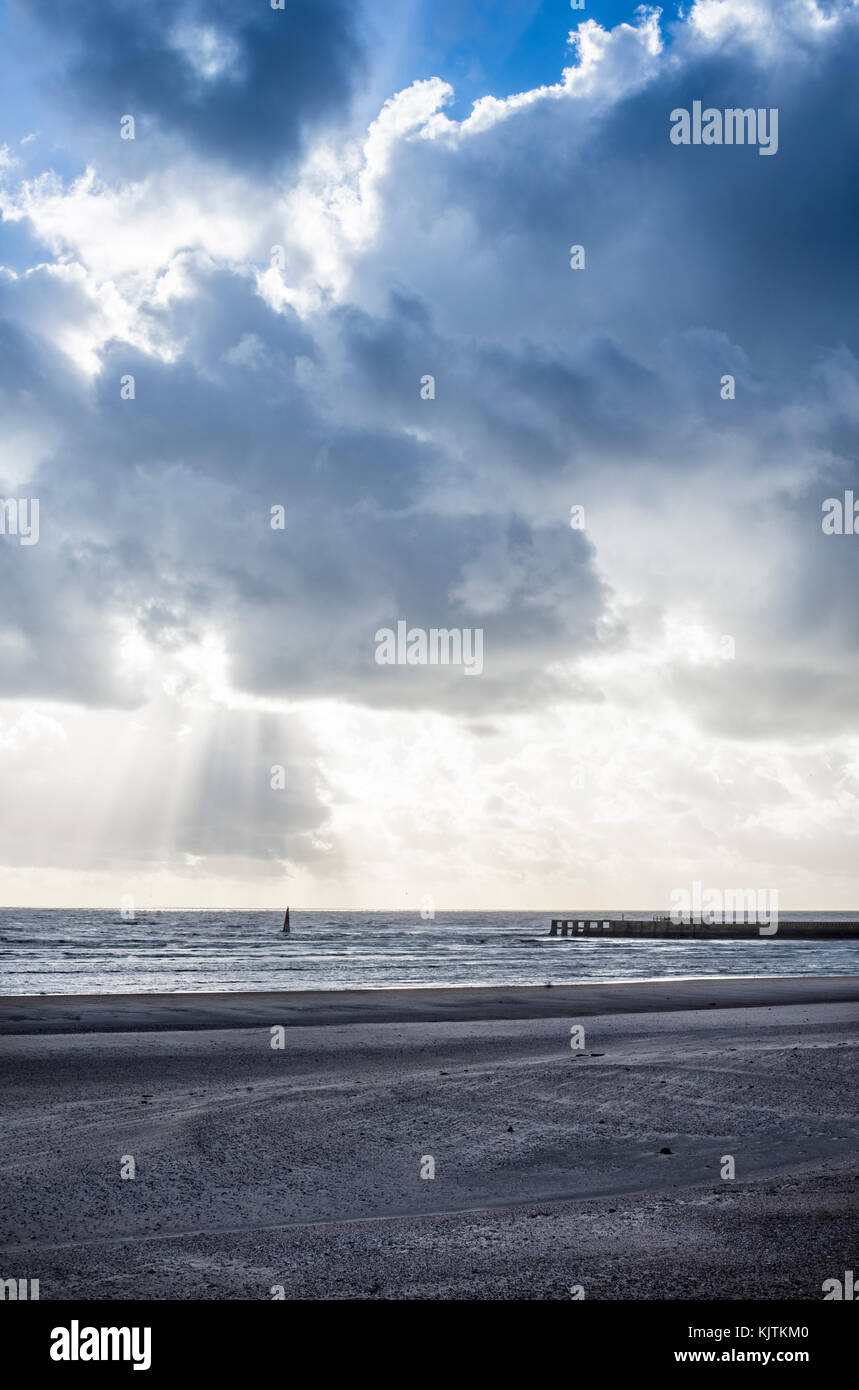 Leeren Strand im Winter, mit Tide in der Kommenden und dramatische Himmel, die Sonne kommt durch Wolken Stockfoto