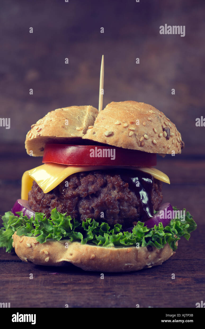 Saftige Beef Burger mit Käse und Gemüse auf dem hölzernen Hintergrund Stockfoto