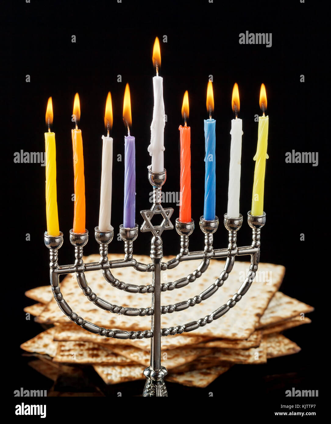 Menorah mit brennenden Kerzen für chanukka auf einem schwarzen Hintergrund. matza im Hintergrund. Stockfoto