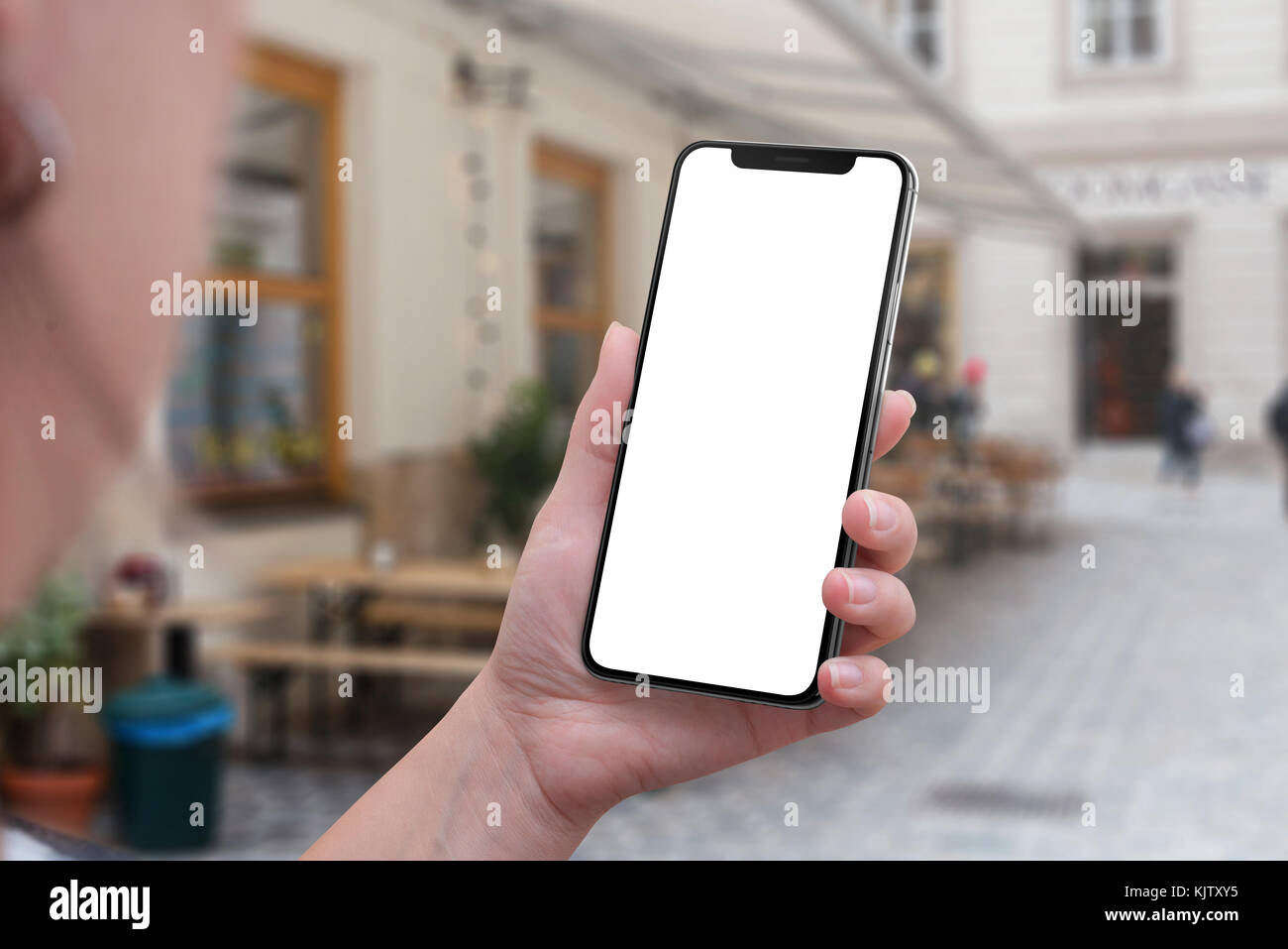 X-Smartphone in der Frau Hand. isolierte Bildschirm für Benutzeroberfläche mockup. Straße der Stadt im Hintergrund. Stockfoto