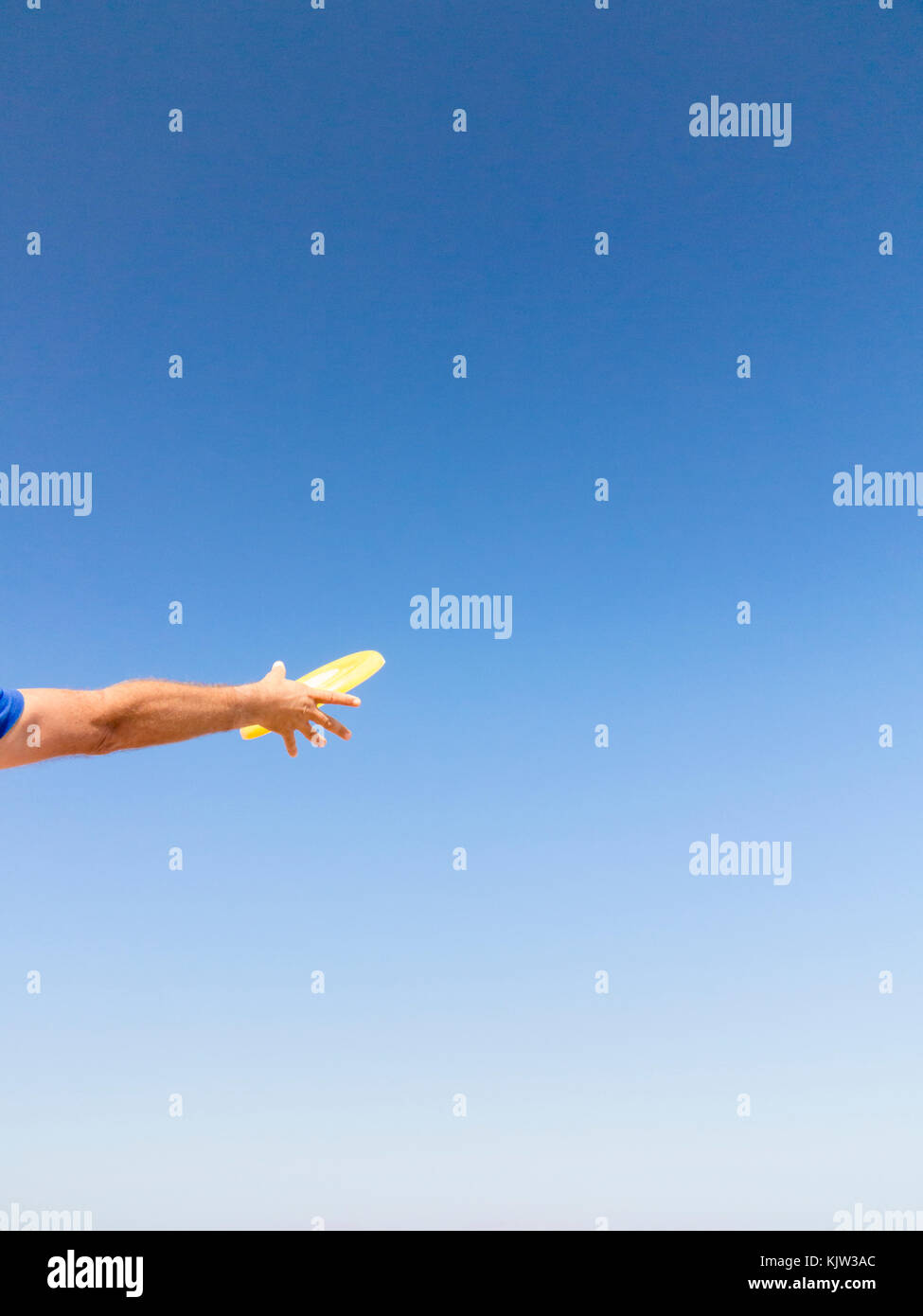 Man fängt einen Frisbee gegen den blauen Himmel Stockfoto