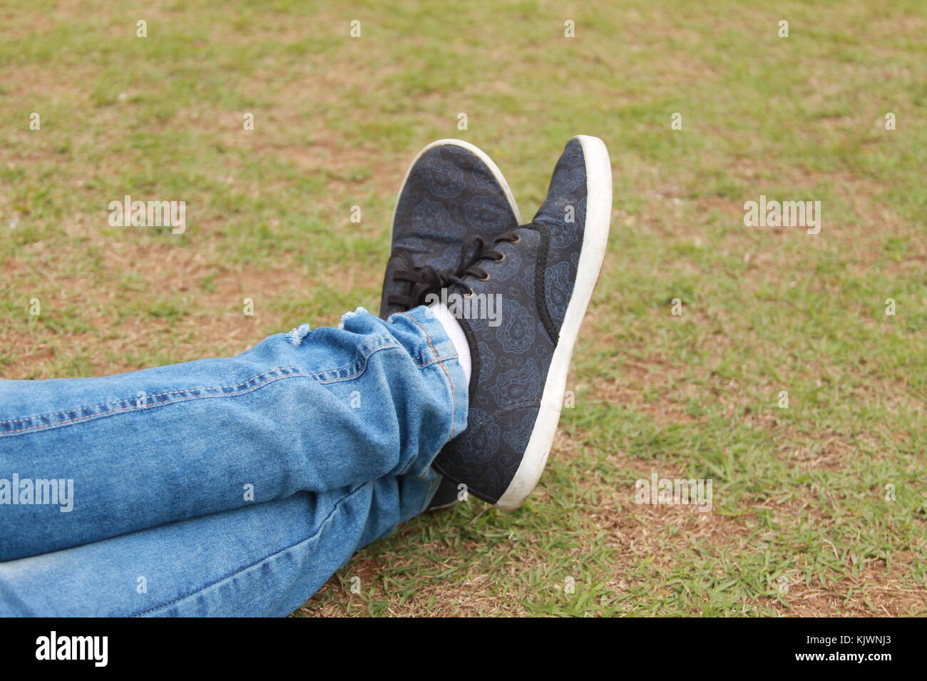 Mädchen liegt auf Gras, in der Nähe von Ihren gekreuzten Beinen Stockfoto