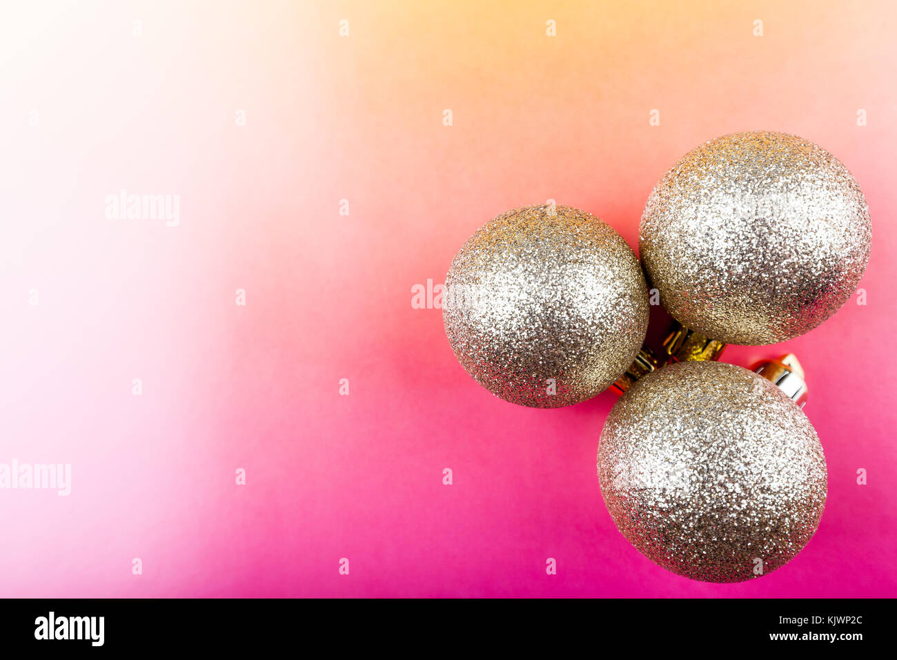 Weihnachtsdekoration, drei goldene Kugeln auf einem farbigen Hintergrund. Stockfoto