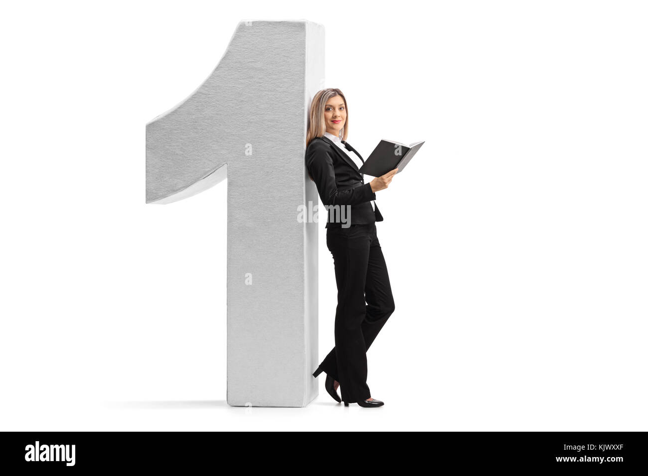 Volle Länge Profil Schuß einer formell gekleidete Frau mit einem Buch gegen einen Karton Nummer eins auf weißem Hintergrund schiefen Stockfoto
