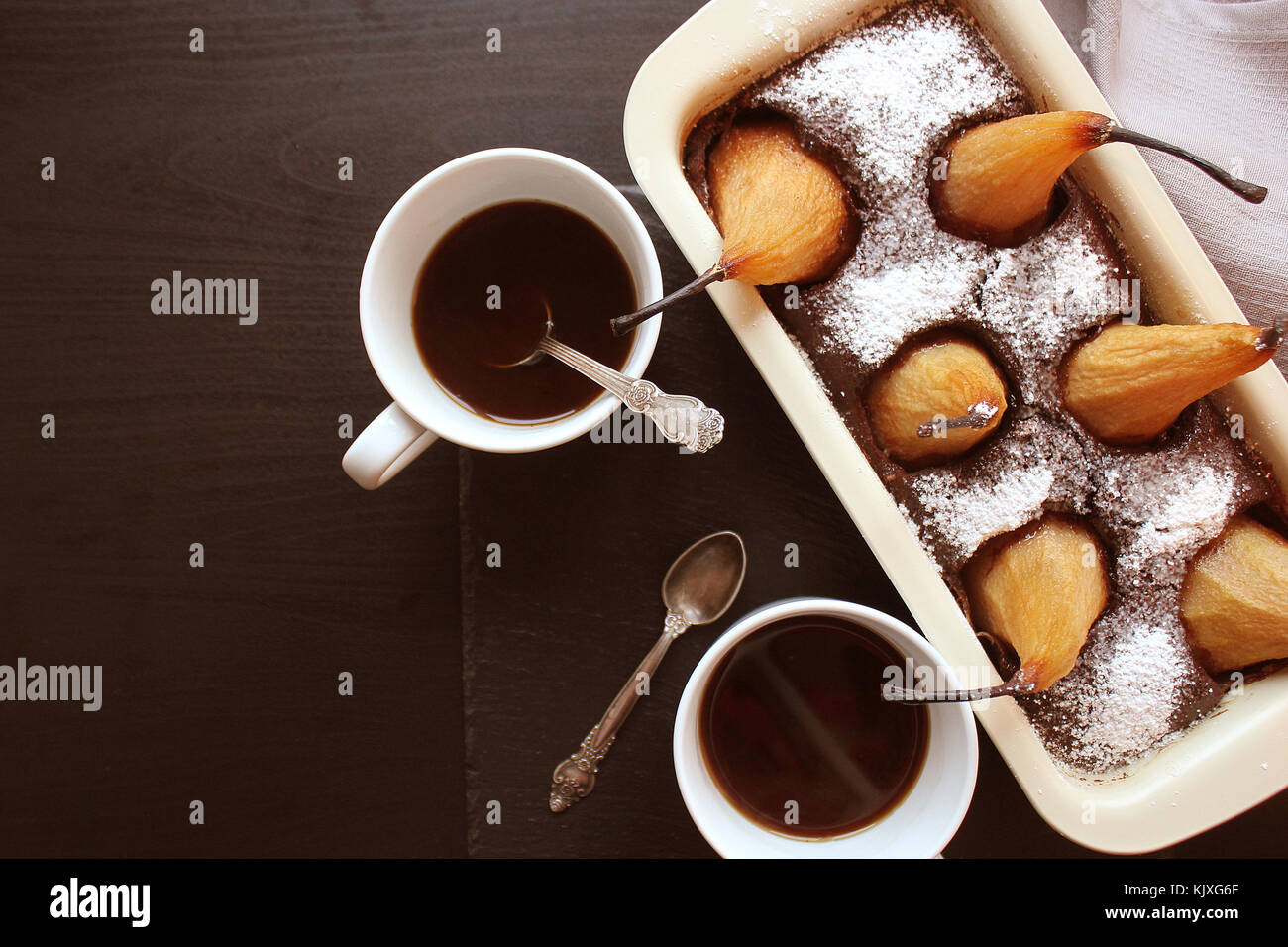 Schokolade Brot Kuchen mit ganzen Birnen gebackene Innen und zwei Tassen Kaffee auf dunklem Hintergrund. Ansicht von oben Stockfoto