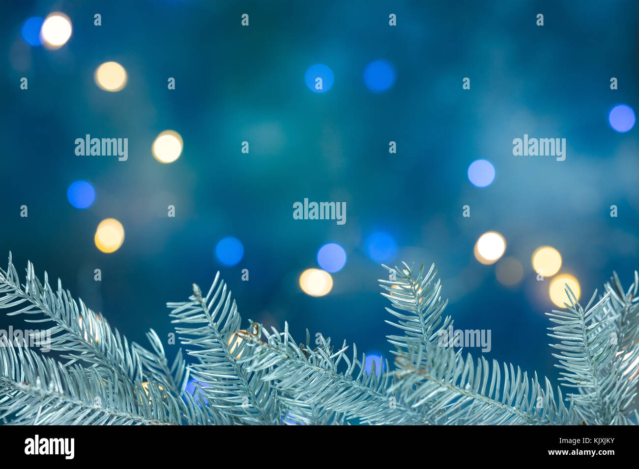 Silver christmas tree branch auf unscharfen Hintergrund blau mit Holiday Lights Stockfoto
