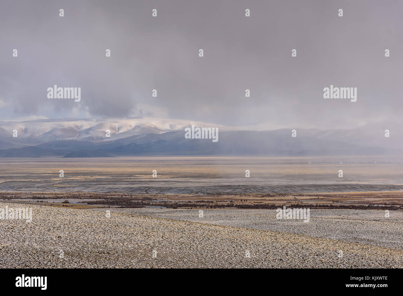 Einen malerischen Blick auf schwere Schneefälle über die Berge, Steppe und ein Dorf in der Ferne auf dem Hintergrund der Himmel mit Gewitterwolken Stockfoto