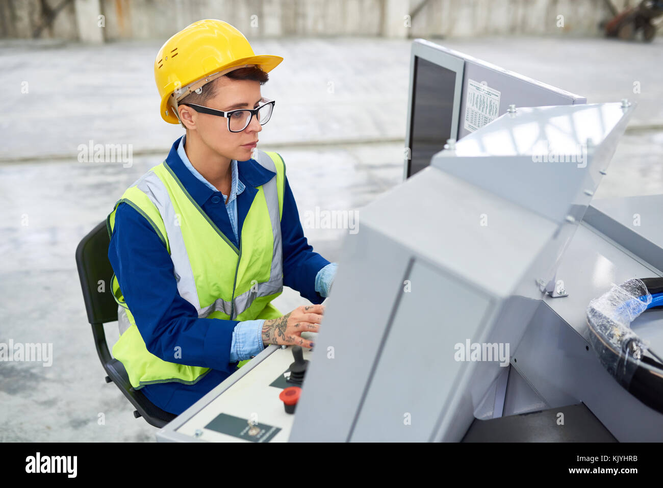 Konzentrierte Werk Mitarbeiter in grüne Weste mit Hilfe der technischen Maschine, während auf dem Armaturenbrett an der Anlage arbeiten Stockfoto