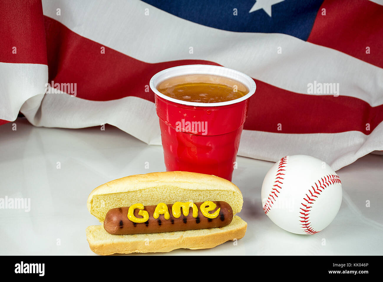 Wort Spiel in Senf auf Hot Dog mit Baseball und Bier in rot Schale und die amerikanische Flagge im Hintergrund Stockfoto