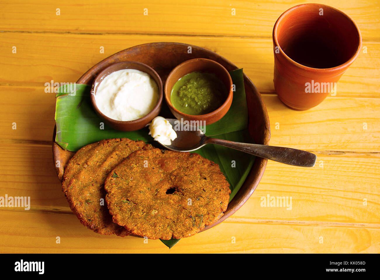 Blick von oben auf die beliebten thalipith Maharashtrian herzhafte Pfannkuchen mit Quark und Pudina Chutney in Ton Geschirr serviert. Stockfoto
