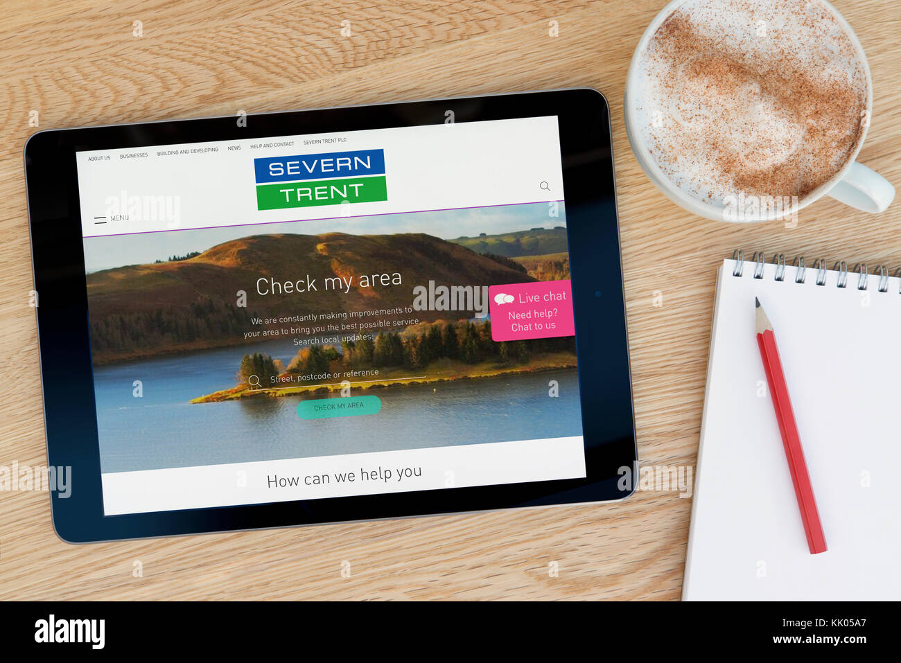 Ein Mann schaut auf die Severn Trent Water Website auf seinem iPad tablet device, Schuß gegen einen hölzernen Tisch top Hintergrund (nur redaktionelle Nutzung) Stockfoto