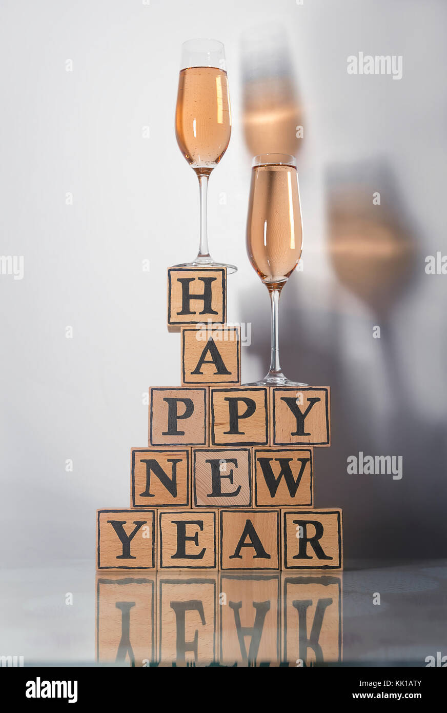 Gläser mit rosigen Champagner eine farbige Schatten und Holzwürfel machen Form der text Frohes neues Jahr aufrecht Stockfoto