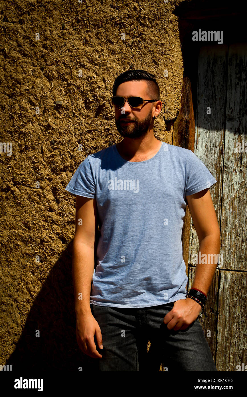 Kaukasische Mann mit Sonnenbrille Hand in der Tasche stand vor der Tür der Schlamm Haus Stockfoto