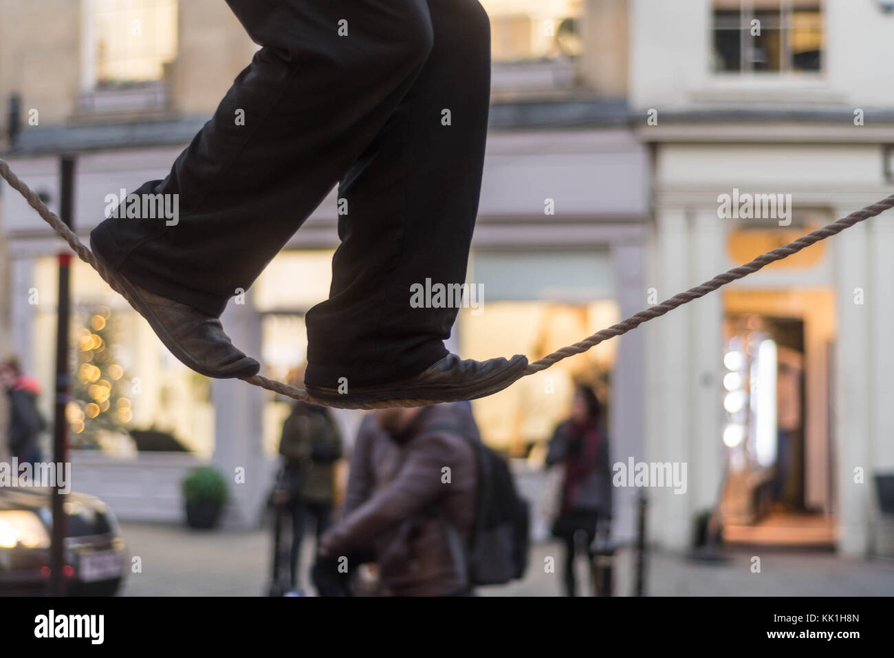 Tight rope Walker Beine. Füße von Acrobat Balancieren auf das Seil im belebten Hauptstraße mit Passanten Stockfoto
