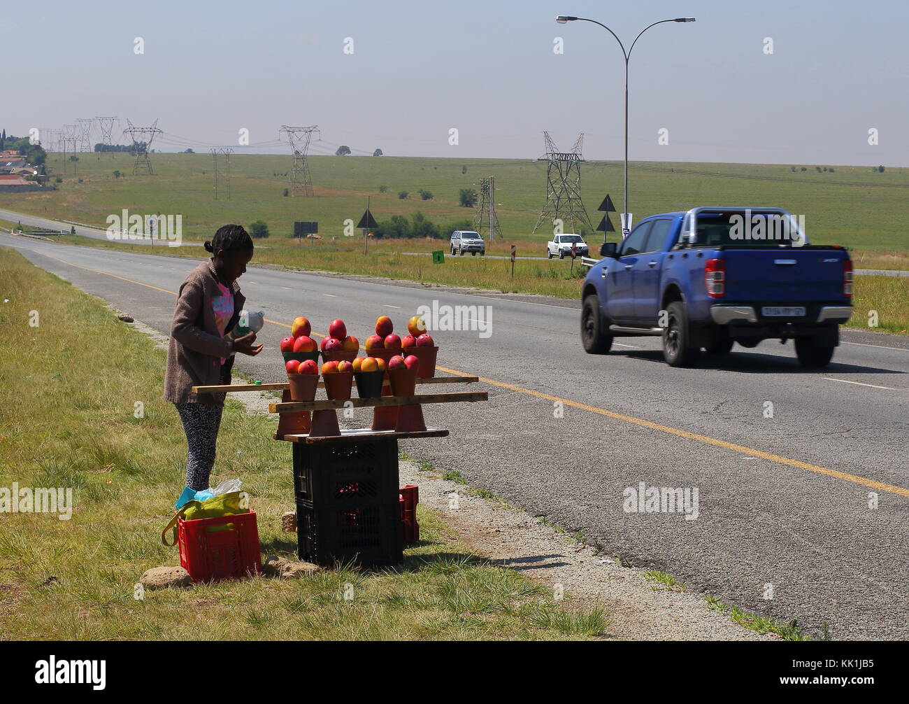 Johannesburg, Südafrika - eine nicht identifizierte Jugend verkauft Mangos an vorbeifahrende Autofahrer, um ein Einkommen zu erzielen, da die Arbeitslosigkeit weit verbreitet ist Stockfoto
