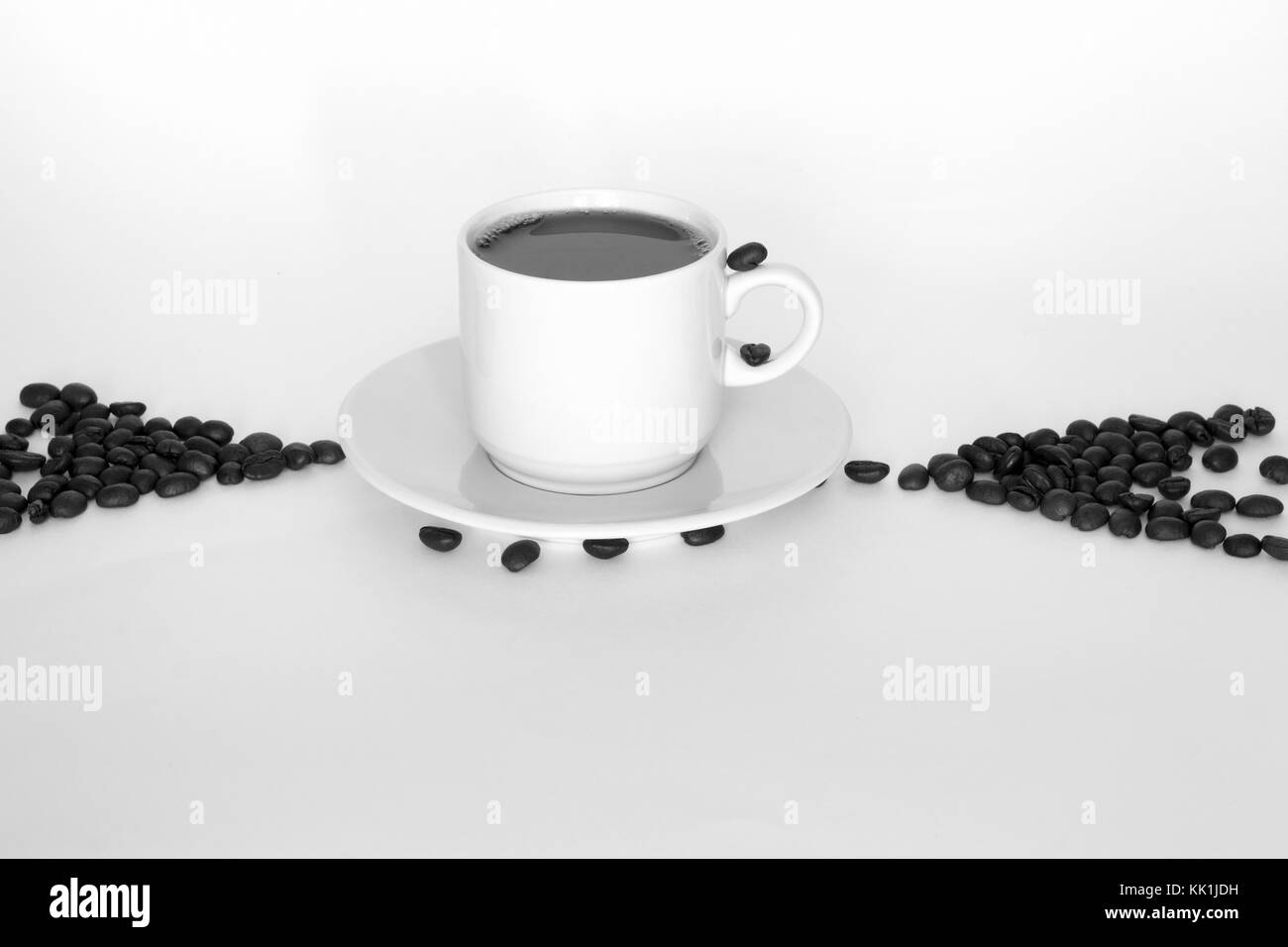 Tasse Kaffee und Kaffeebohnen in Form von Pfeilen auf weißem Hintergrund. Konzept Hinweise. schwarz-weiß Foto Stockfoto