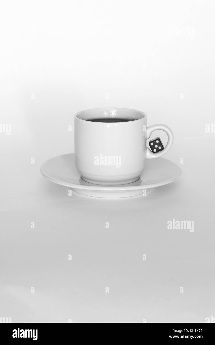 Kaffeetasse mit Würfeln auf weißem Hintergrund. Schwarz und Weiß. Kunst trinken Konzept. Trinken für Spieler, Geschäftsmann, Leader. Vertikale Stockfoto