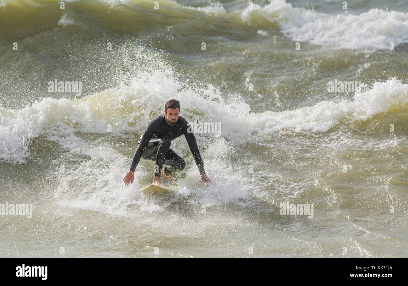 Man surfen auf rauer See einer Welle auf einem Surfbrett, in Großbritannien. Stockfoto