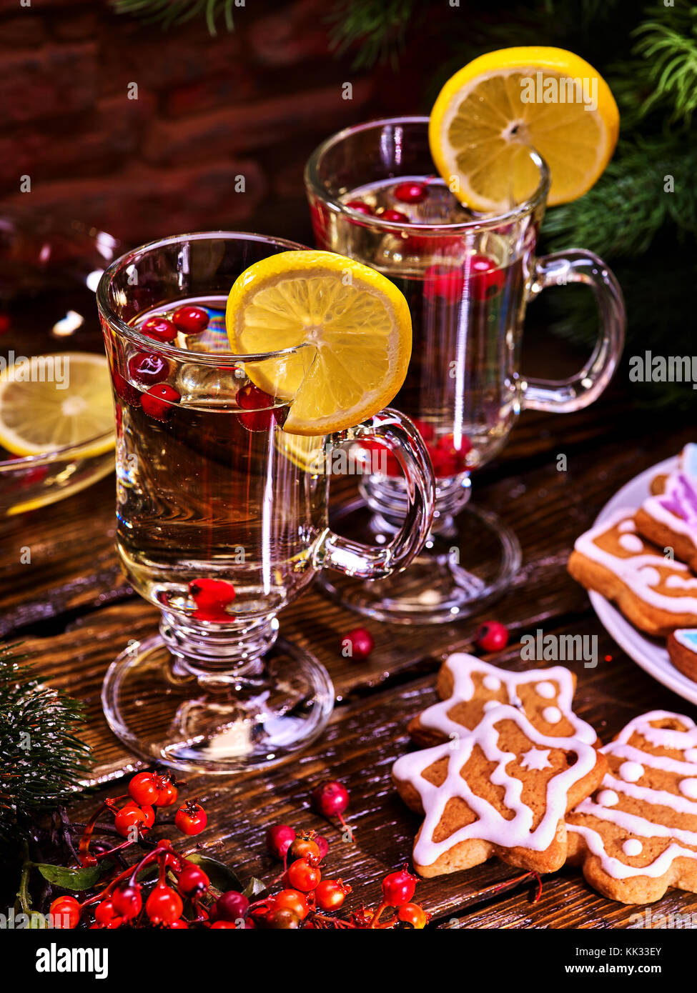 Weihnachtsplätzchen auf Platte mit Tannenzweigen. Weihnachten noch Leben mit paar Becher Dekoration Zitronenscheibe heißen Getränk auf Holztisch. romantische Atmosphäre Stockfoto