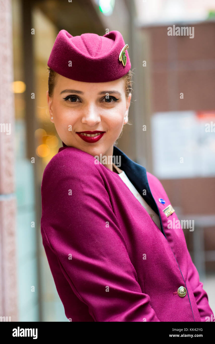 Junge attraktive Frauen arbeiten als Flugbegleiter für Qatar Airways auf London Zwischenstopp. Hübsches lächeln, glücklich und warten auf Flug nach Doha. Stockfoto