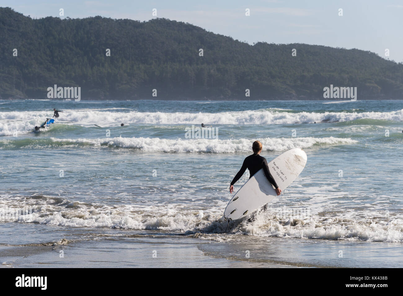 Chesterman Strand in der Nähe von Tofino, BC, Kanada (September 2017) - Frau mit einem Surfbrett. Stockfoto
