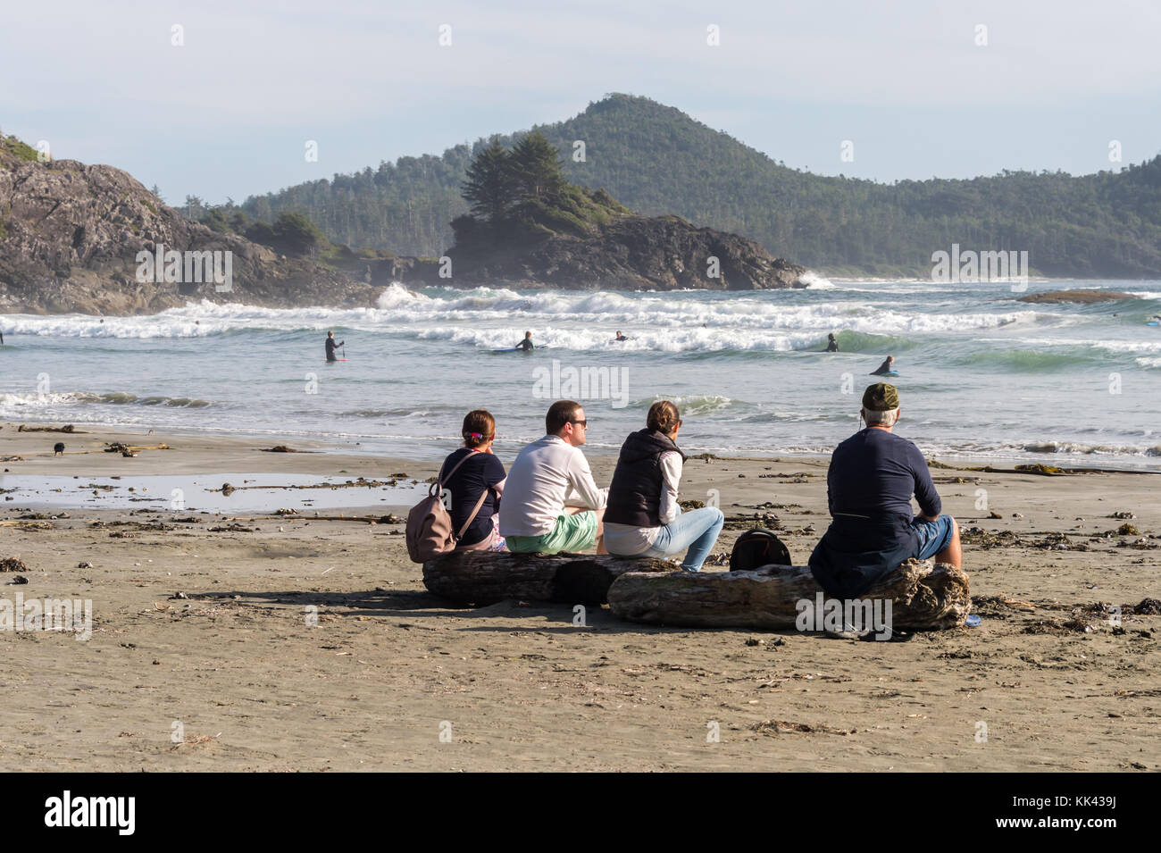 Chesterman Strand in der Nähe von Tofino, BC, Kanada (September 2017) - Familie auf Holzklotzholz sitzen. Stockfoto