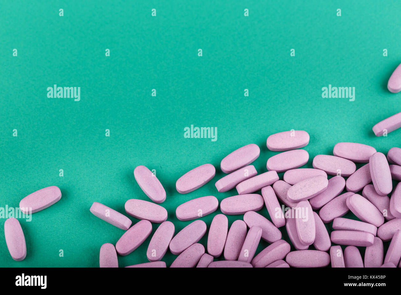 Große rosa Tabletten auf grünem Hintergrund verstreut. Behandlung von  Vitaminmangel Vitamine Stockfotografie - Alamy