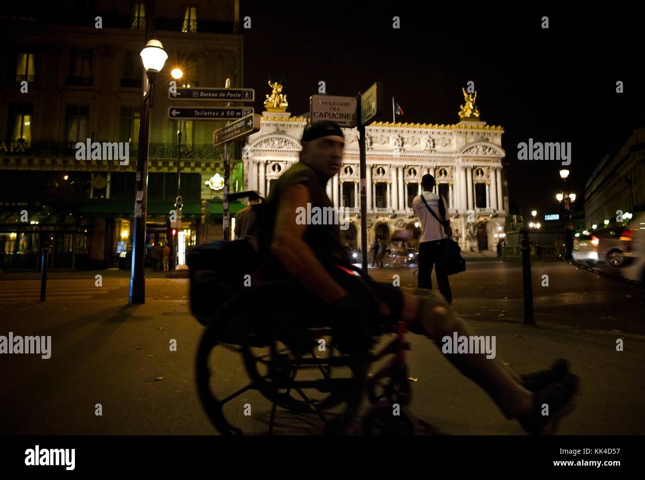 Städtische Armut - 27/07/2012 - - Behinderte durch Paris schlendernd, mit seinen Angelegenheiten in der Nacht, die hinter seinem Rollstuhl hängen, Ort der Oper - Sylvain Leser / Le Pictorium Stockfoto