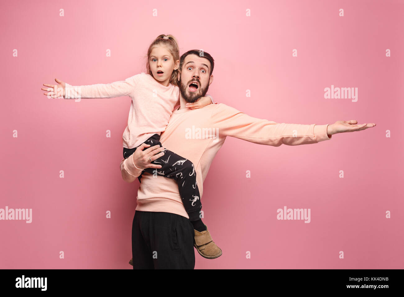 Freundliche Vater spielt mit Tochter auf Rosa Stockfoto