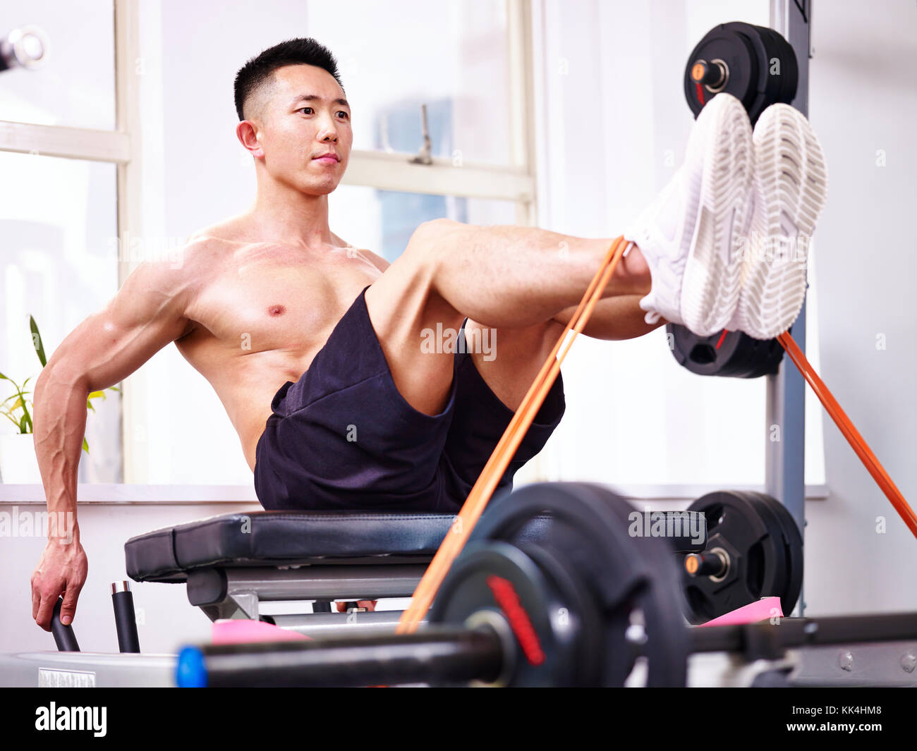 Asiatische männlichen Bodybuilder trainieren im Fitnessstudio mit einem Widerstand Band. Stockfoto
