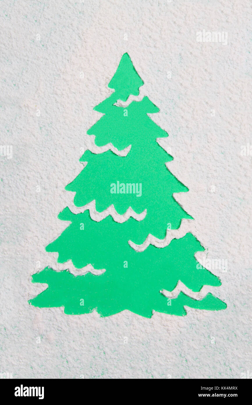 Ein von einer Schablone in der Form eines Weihnachtsbaums aus Mehl auf einem grünen Hintergrund verfolgen. Ideen für festliche Backen und dekorieren Stockfoto