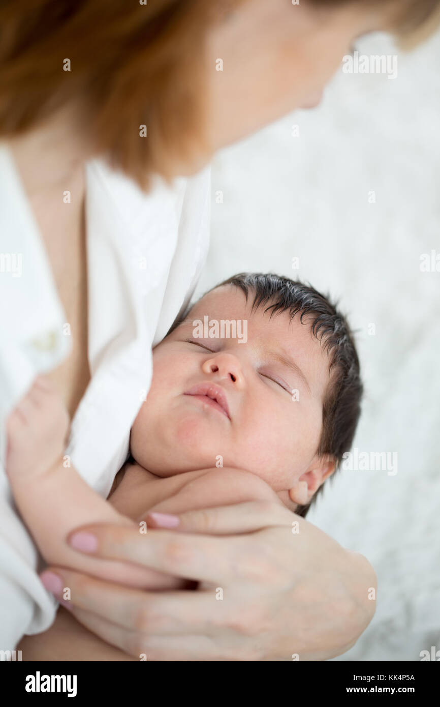 Mutter ihr schlafendes Baby Holding im Bett Stockfoto