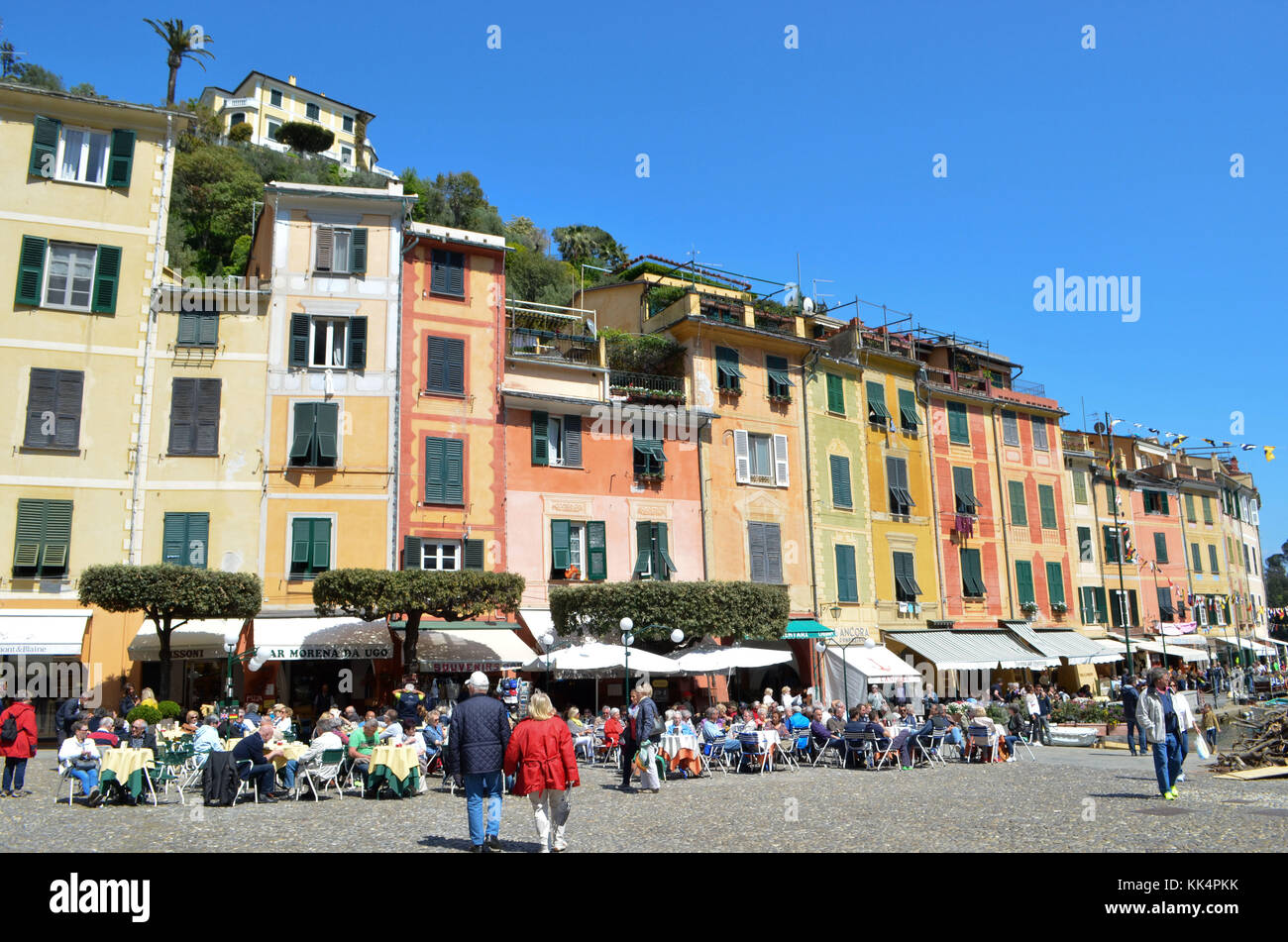 Italien, Ligurien: Portofino. Touristen auf Terrassen, die auf dem Platz des kleinen Dorfes mit bunten Häusern geschützt in einer Bucht. Ein paar der älteren Menschen Stockfoto